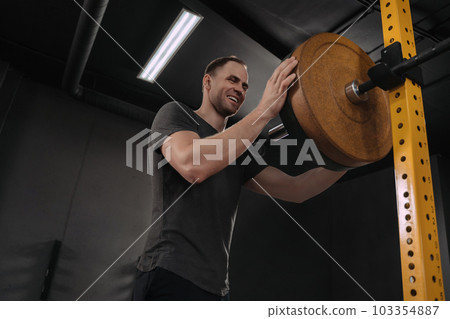 Happy smiling crossfit athlete putting on more weights on barbell Happy smiling crossfit athlete putting on more weights on barbell 103354887