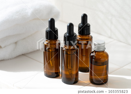 White towel and brown cosmetic glass container on tile 103355823