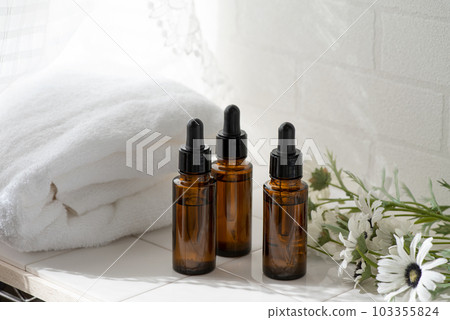 一條白毛巾、鮮花和一個棕色的玻璃化妝品瓶 103355824