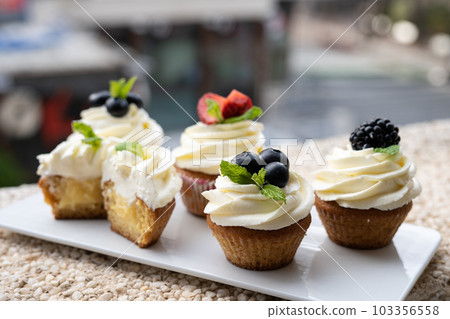 Cupcakes with different fruits on a white plate close-up. 103356558