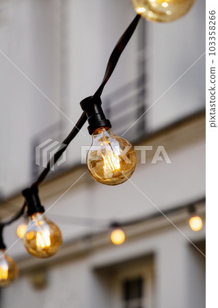 Bright light bulbs on a wire on a wall background Bright light bulbs on a wire on a wall background 103358266