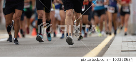 Marathon runners running on city road, large group of runners Marathon runners running on city road, large group of runners 103358684