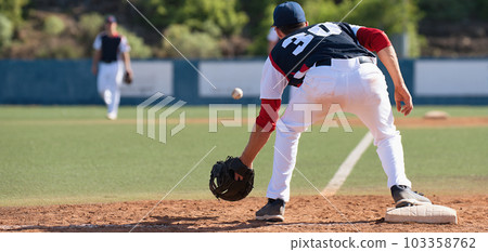 Baseball pitcher, catching ball while on field during sunny day 103358762