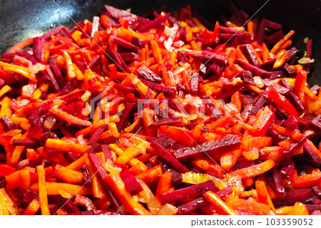 Cooking healthy food from vegetables. Chopped carrots with beetroot in a frying pan. 103359052