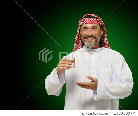Arab man holding glass of water, conveying sense of healthy living and mindfulness. It emphasizes importance of hydration and wellness in Middle Eastern culture, making it ideal for use in health 103359077