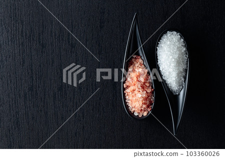 White sea salt and pink Himalayan salt on a black ceramic table. White sea salt and pink Himalayan salt on a black ceramic table. 103360026