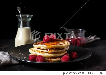 pancake spread with honey and raspberry on a plate accompanied with milk 103360182
