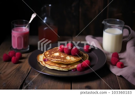 pancake spread with honey and raspberry on a plate accompanied by milk and fruit juice 103360183