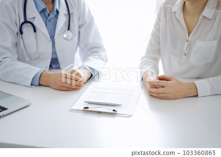 Doctor and patient discussing current health questions while sitting near of each other and using clipboard at the table in clinic, just hands closeup. Medicine concept 103360865