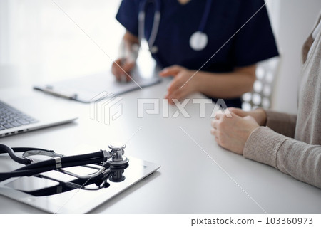 Stethoscope lying on the tablet computer in front of a doctor and patient at the background. Medicine, healthcare concept 103360973