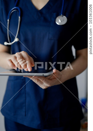 Doctor woman using tablet computer while standing near panorama window in clinic, close up. Physician or surgeon at work. Medicine concept 103361006