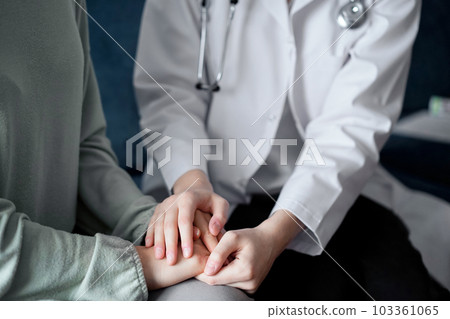 Doctor and patient sitting at green sofa. The focus is on female physician's hands reassuring woman, close up. Medicine concept Doctor and patient sitting at green sofa. The focus is on female physician's hands reassuring woman, close up. Medicine concept 103361065