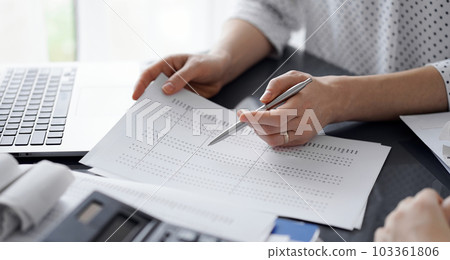 Female accountant pointing with a pen into audit paper while explaining tax counting results, close up. Business audit and finance concepts Female accountant pointing with a pen into audit paper while explaining tax counting results, close up. Business audit and finance concepts 103361806