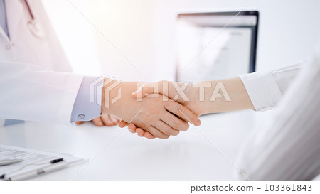 Doctor and patient shaking hands while sitting opposite of each other at the table in clinic, just hands close up. Medicine concept 103361843