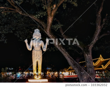 A sculptural image of a multi-faced and multi-armed Hindu deity illuminated in the evening on a street in Siem Reap. A sculptural image of a multi-faced and multi-armed Hindu deity illuminated in the evening on a street in Siem Reap. 103362032