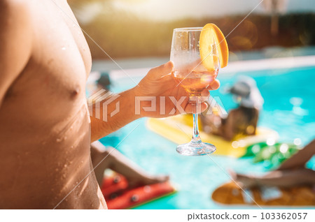 Group of friends in swimsuit drink a cocktail in a swimming pool Group of friends in swimsuit drink a cocktail in a swimming pool 103362057