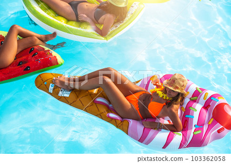 Friends in swimsuit in the pool getting a tan Friends in swimsuit in the pool getting a tan 103362058