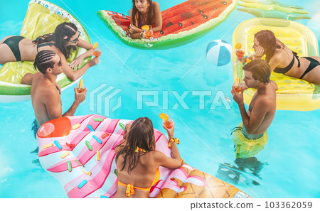 Group of friends in swimsuit drink a cocktail in a swimming pool Group of friends in swimsuit drink a cocktail in a swimming pool 103362059