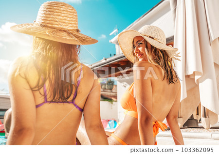 Group of friends tan and relax at the pool 103362095