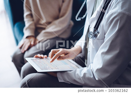 Doctor woman and kid boy patient at home. The pediatrician using tablet computer while filling up medical records, close up. Medicine, healthcare concept 103362162