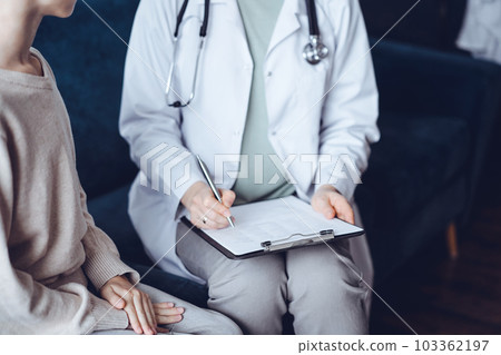 Doctor woman and kid boy patient at home medical exam. The pediatrician filling up medical form on clipboard, close up. Medicine, healthcare concepts 103362197