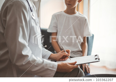 Doctor woman and kid patient at home. The pediatrician filling up medical form on clipboard, close up. Medicine, healthcare concepts 103362207