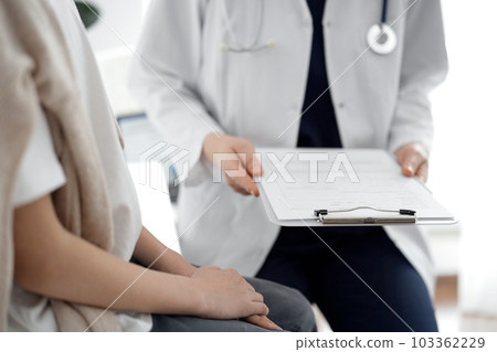 Doctor and child patient. The physician is holding clipboard with medication history records form near a boy. The concept of ideal health in medicine Doctor and child patient. The physician is holding clipboard with medication history records form near a boy. The concept of ideal health in medicine 103362229