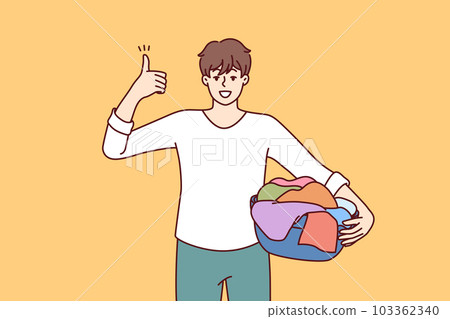 Man householder with laundry in basin shows thumbs up recommending quality laundry detergent Man householder with laundry in basin shows thumbs up recommending quality laundry detergent 103362340