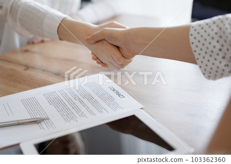 Business people shaking hands above contract papers just signed on the wooden table, close up. Lawyers at meeting. Teamwork, partnership, success concept Business people shaking hands above contract papers just signed on the wooden table, close up. Lawyers at meeting. Teamwork, partnership, success concept 103362360