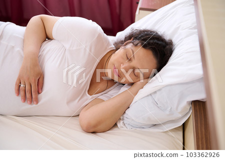 Close-up peaceful attractive young 35s expectant mother resting, sleeping, napping, lying alone in bedroom, take break, renew energy looking carefree. Pregnancy concept. Pregnancy trimester third 103362926