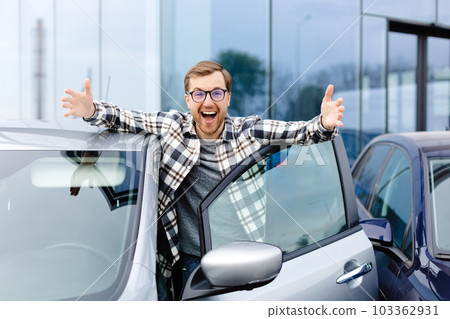 Great Car. Cheerful guy standing near auto, gesturing thumbs up buying vehicle in dealership center 103362931