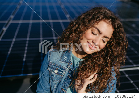 Portrait of young woman on roof with solar panels. 103363134