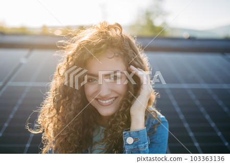 Portrait of young woman on roof with solar panels. 103363136