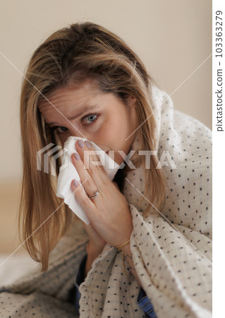 Portrait of young sick woman sneezing at bedroom. Portrait of young sick woman sneezing at bedroom. 103363279