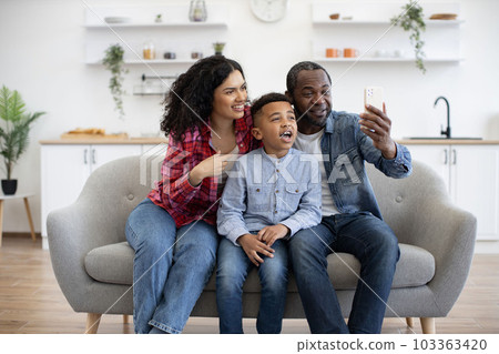 Spouses with son having online phone call in lounge at home Spouses with son having online phone call in lounge at home 103363420