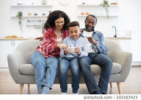 Couple with kid playing video game on phone online Couple with kid playing video game on phone online 103363423