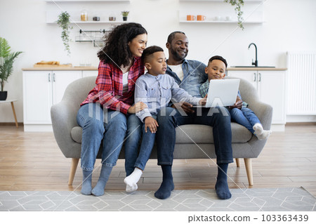 Four-person family watching movie on laptop at home Four-person family watching movie on laptop at home 103363439