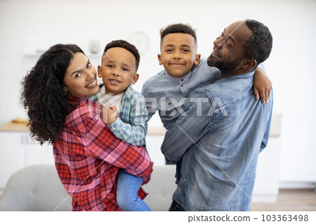 Man and woman with sons looking over shoulder in apartment 103363498