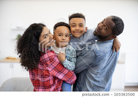 Man and woman with sons looking over shoulder in apartment 103363500