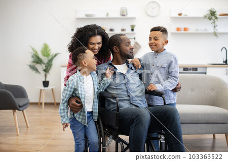 Sons talking with mom and dad in wheelchair in apartment 103363522