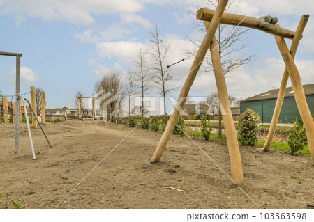 an outdoor play area with swings and wooden poles in the fore - image is taken from below, it's blue sky an outdoor play area with swings and wooden poles in the fore - image is taken from below, it's blue sky 103363598