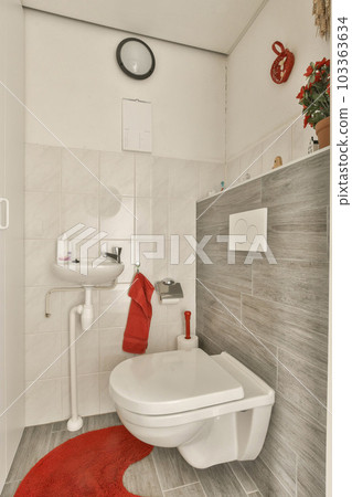 a small bathroom with red rugs on the floor and white tiles on the walls, along with a toilet 103363634