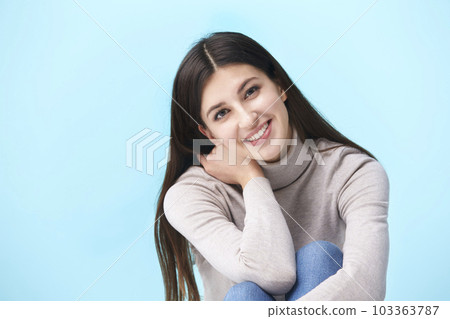 studio portrait of a beautful caucasian woman, sitting on floor, looking at camera smiling,  103363787