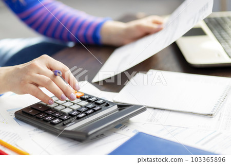 Woman using calculator for calculate domestic bills at home, doing paperwork 103365896