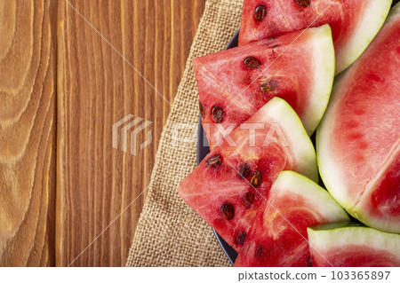 Fresh red watermelon pieces on a black plate on a wooden table Fresh red watermelon pieces on a black plate on a wooden table 103365897