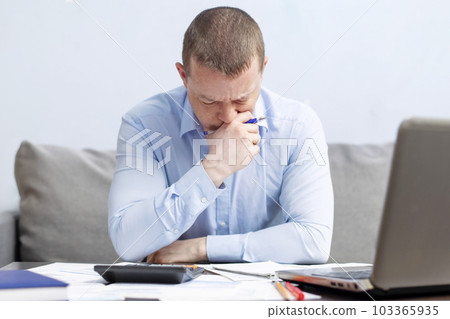 Distressed man sit at desk paying bills feel stressed having financial problems 103365935