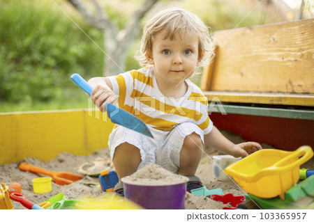 A little boy playing in the sandbox at the playground outdoors. A little boy playing in the sandbox at the playground outdoors. 103365957