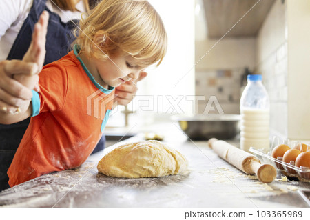 Happy family cooking and kneading dough on a wooden table in the kitchen 103365989