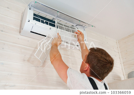 A man replaces and cleans the air cleaner filter from the air conditioner. 103366059