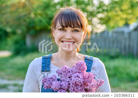 Outdoor portrait of mature happy woman with lilac bouquet Outdoor portrait of mature happy woman with lilac bouquet 103366311